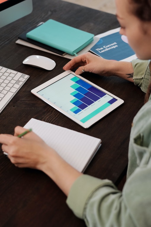 A woman taking notes and looking at a tablet